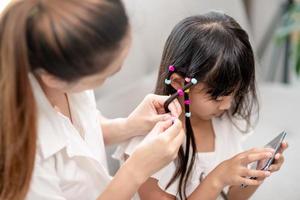 Young Asian mother tying daughter's hair photo