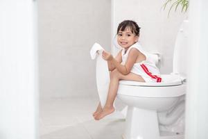 The little girl is sitting on the toilet suffering from constipation or hemorrhoid. photo