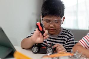 Young asia student remotely learn online at home  in coding robot car and electronic board cable in STEM, STEAM, mathematics engineer science technology computer code in robotics for kids. photo