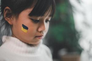 A child with the flag of Ukraine is crying. Sadness longing hope. Children's tears from the war. Evacuation of civilians. Freedom to Ukraine photo