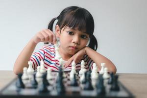 Asian little girl playing chess at home.a game of chess photo