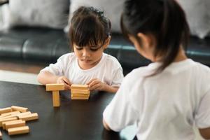 Two happy siblings playing a game with wooden blocks at home joyfully photo