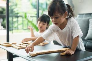 Two happy siblings playing a game with wooden blocks at home joyfully photo