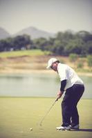 jugador de golf en el putting green golpeando la bola en un agujero.color vintage foto