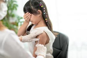 Vaccination concept. Female doctor vaccinating cute little girl in clinic photo