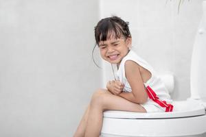 la niña está sentada en el baño sufriendo de estreñimiento o hemorroides. foto