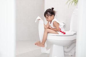 The little girl is sitting on the toilet suffering from constipation or hemorrhoid. photo