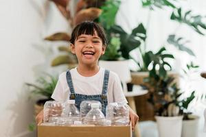 Girl looking at camera and holding plastic bottles for recycling photo