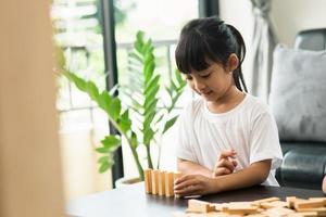 Two happy siblings playing a game with wooden blocks at home joyfully photo