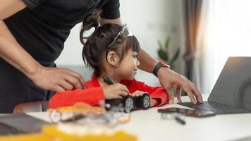 STEM education, Asian girl and father learning programming process of new robot technology. Happy family members relationship, Studying anywhere anytime to learn together at home photo