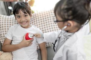 Two cute children play doctor and hospital using stethoscope. Friends girls having fun at home or preschool. photo