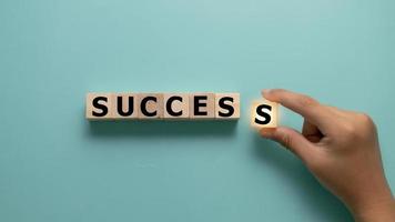 Success instead of stress symbol. Hand put cubes and changes the concept to Success. Beautiful grey background. Business psychological success or stress concept. Copy space photo