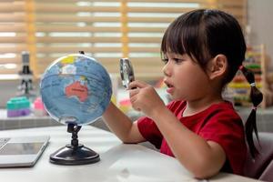 Asian little girl is learning the globe model, concept of save the world and learn through play activity for kid education at home. photo