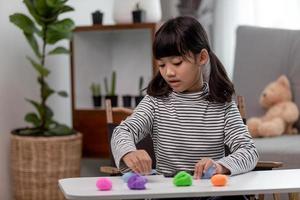 The little girl is learning to use colorful play dough in a well lit room photo