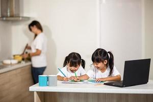 coronavirus covid-19 y aprendizaje desde el hogar, concepto de niño escolar en casa. los niños pequeños estudian en línea aprendiendo desde casa con una computadora portátil. foto