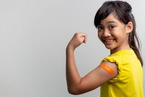 concepto de vacunas covid 19 para niños. estudio un retrato de una adorable niña asiática después de recibir su primera dosis de vacuna. inmune, seguro, disponible, regreso a la escuela. foto