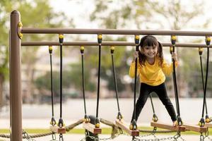 summer, childhood, leisure and people concept - happy little girl on children playground climbing frame photo
