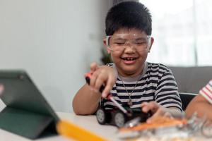Young asia student remotely learn online at home  in coding robot car and electronic board cable in STEM, STEAM, mathematics engineer science technology computer code in robotics for kids. photo