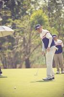 Golf player at the putting green hitting ball into a hole.Vintage color photo