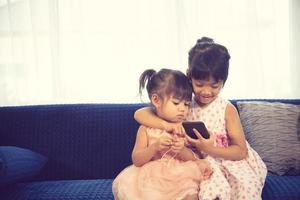 Children listening to music while sitting on a couch photo