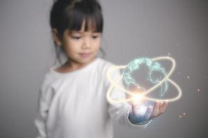 niña linda sosteniendo un planeta tierra luminoso en sus manos. día de la Tierra. foto