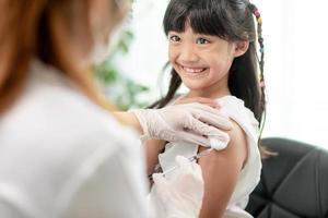 concepto de vacunación. doctora vacunando a una niña linda en la clínica foto