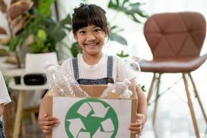 Girl looking at camera and holding plastic bottles for recycling photo