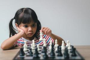 Asian little girl playing chess at home.a game of chess photo