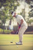 jugador de golf en el putting green golpeando la bola en un agujero.color vintage foto