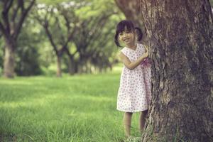 Little girl looking out from behind a birch tree photo