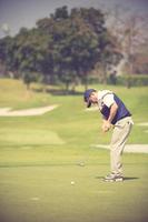 jugador de golf en el putting green golpeando la bola en un agujero.color vintage foto