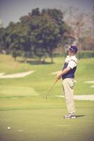 Golf player at the putting green hitting ball into a hole.Vintage color photo