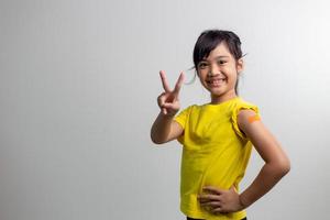 COVID 19 Vaccines for Kids concept. Studio a portrait of an adorable Asian girl after getting his first dose of vaccine. Immune, Safe, Available, Back to school. photo