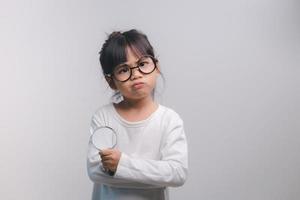 Little girl child holding a magnifying glass on white background photo