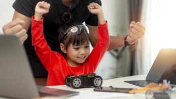 STEM education, Asian girl and father learning programming process of new robot technology. Happy family members relationship, Studying anywhere anytime to learn together at home photo