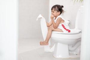 The little girl is sitting on the toilet suffering from constipation or hemorrhoid. photo