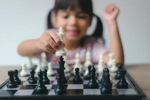 niña asiática jugando al ajedrez en casa.un juego de ajedrez foto