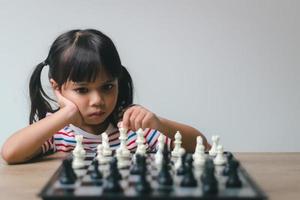 Asian little girl playing chess at home.a game of chess photo