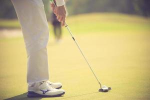 jugador de golf en el putting green golpeando la bola en un agujero.color vintage foto