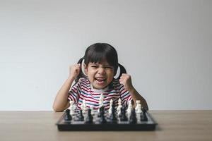 Asian little girl playing chess at home.a game of chess photo