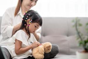 Young Asian mother tying daughter's hair photo