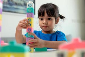 Adorable little girl playing toy blocks in a bright room photo