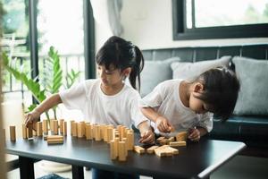 Two happy siblings playing a game with wooden blocks at home joyfully photo