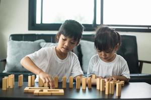 Two happy siblings playing a game with wooden blocks at home joyfully photo