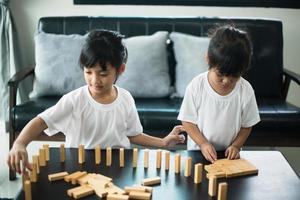 Two happy siblings playing a game with wooden blocks at home joyfully photo