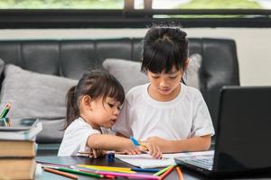 Covid-19 Coronavirus and Learning from home, Home school kid concept. Little children study online learning from home with laptop. photo