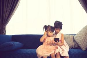 Children listening to music while sitting on a couch photo