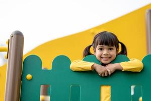 Asian little girl enjoys playing in a children playground, Outdoor portrait photo