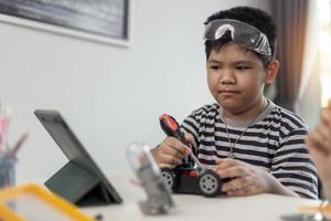 Young asia student remotely learn online at home  in coding robot car and electronic board cable in STEM, STEAM, mathematics engineer science technology computer code in robotics for kids. photo