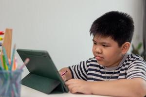 Kid self isolation using tablet for his homework,Child doing using digital tablet searching information on internet during covid 19 lock down,Home schooling,Social Distance,E-learning online education photo